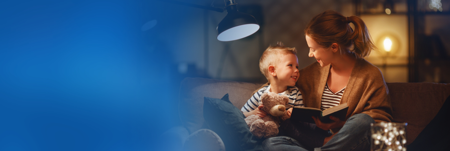 Mother and child reading a book by lamplight